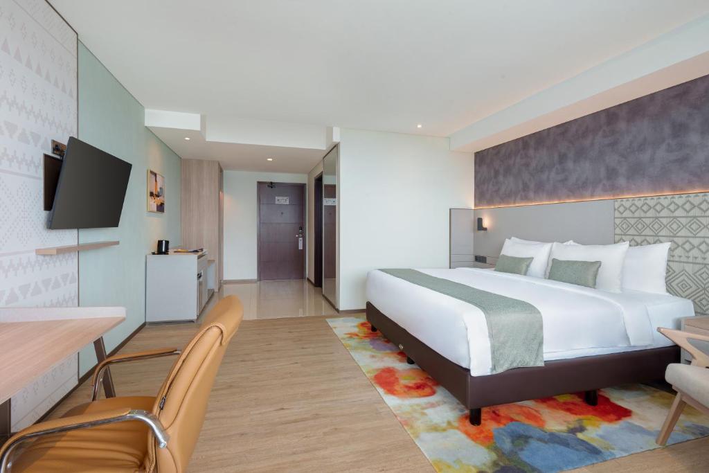 a hotel room with a bed and a table and chairs at Golden Tulip Springhill Lampung in Bandar Lampung