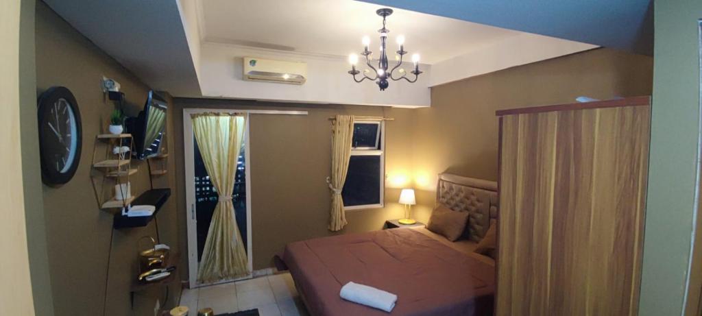 a small bedroom with a bed and a chandelier at Younz Apartemen By Margonda Residence 2 in Pondokcina