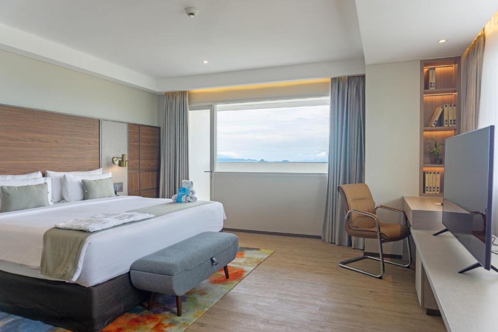 a hotel room with a large bed and a desk at Golden Tulip Springhill Lampung in Bandar Lampung