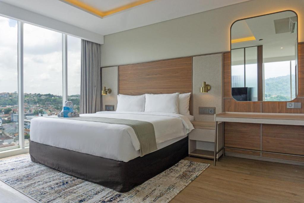 a hotel room with a large bed and a mirror at Golden Tulip Springhill Lampung in Bandar Lampung