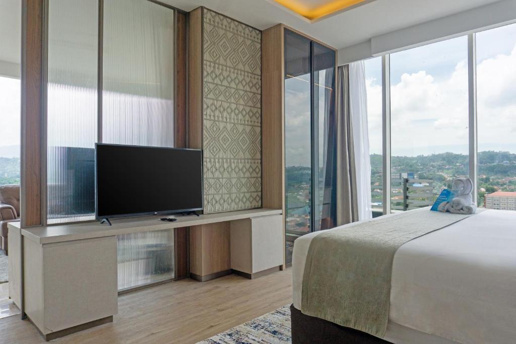 a bedroom with a large bed and a flat screen tv at Golden Tulip Springhill Lampung in Bandar Lampung