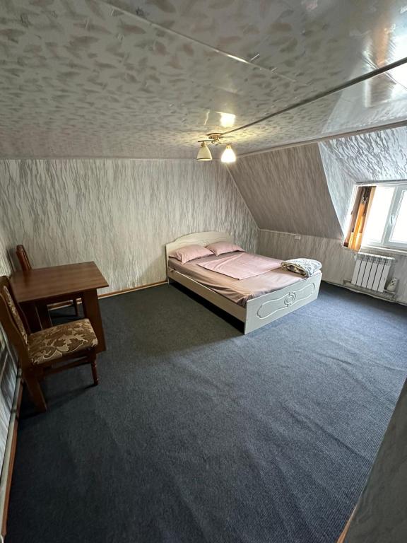 a small bedroom with a bed and a table at Комплекс Тимур in Taūtürgen