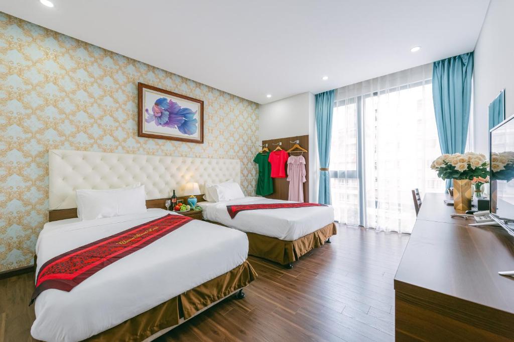 a hotel room with two beds and a desk at New Century Hotel in Hanoi