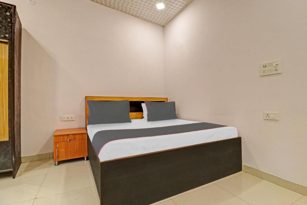 een kleine slaapkamer met een bed en een nachtkastje bij Capital O Hotel Peeragarhi Near M2K Cinemas Rohini in New Delhi
