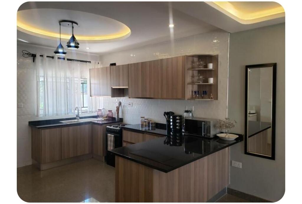 a kitchen with wooden cabinets and a black counter top at The V Space in Lusaka