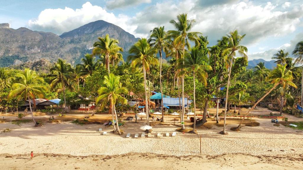 a beach with palm trees and mountains in the background at Hill Myna Beach Cottages in Sabang
