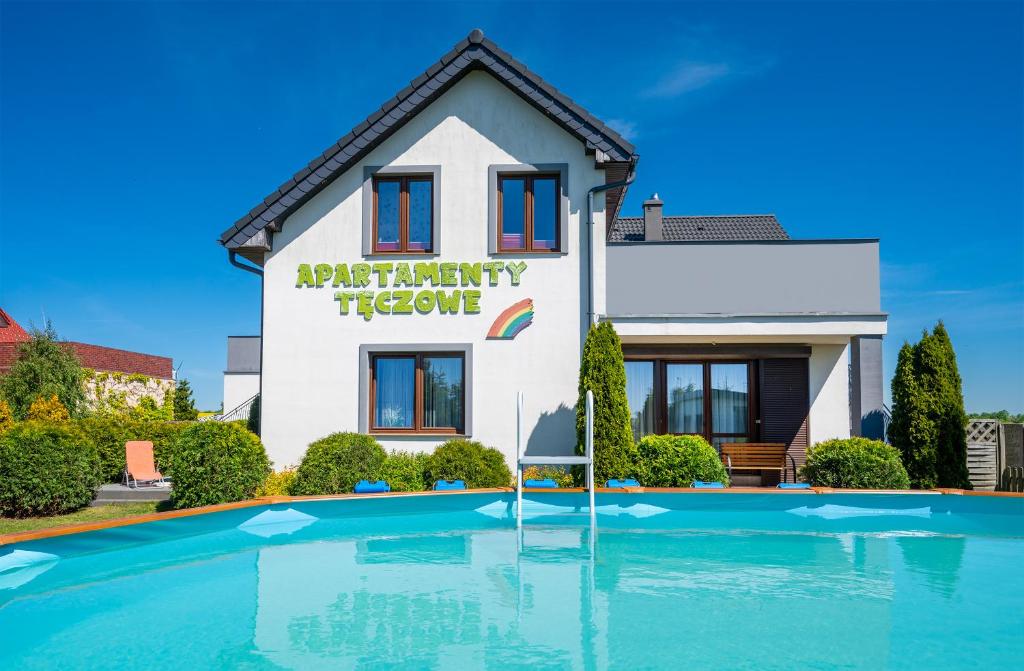 a house with a swimming pool in front of it at Apartamenty Tęczowe in Darłówko
