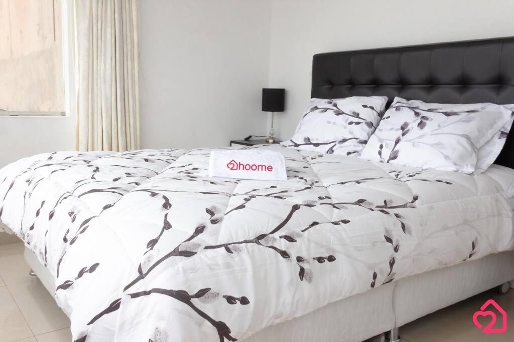 a bed with a white comforter with a sign on it at Departamento con vista de Lima in Lima
