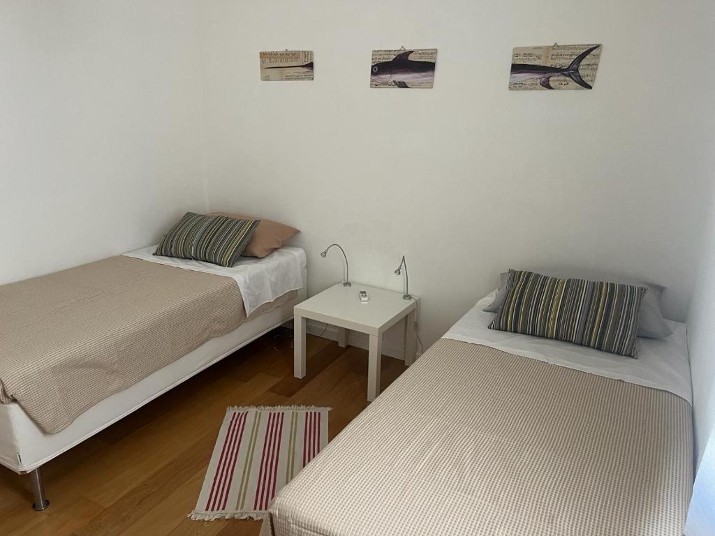 two beds in a small room with a table at CasaNostra11 centro città e mare wifi 2 camere in Trapani