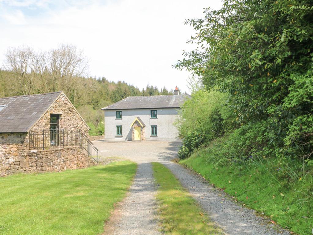 una grande casa bianca con un fienile e una strada sterrata di Coffeys a Ballymacarbry