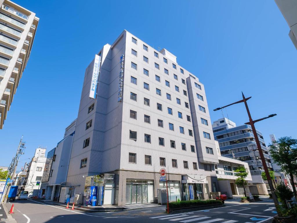 a white building on the corner of a street at Matsuyama New Grand Hotel in Matsuyama
