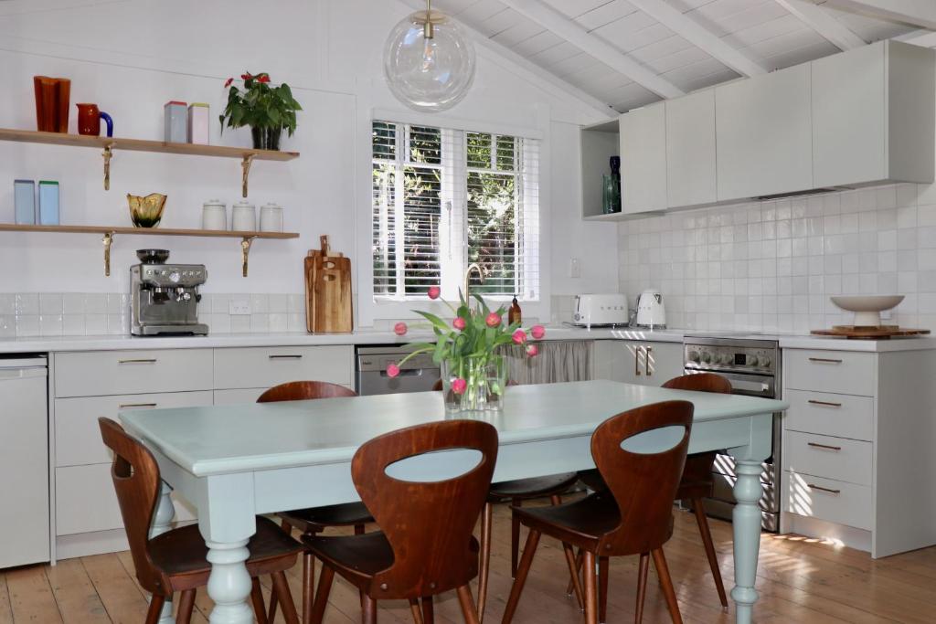 a white kitchen with a white table and chairs at The Moreporks Cottage in Ostend