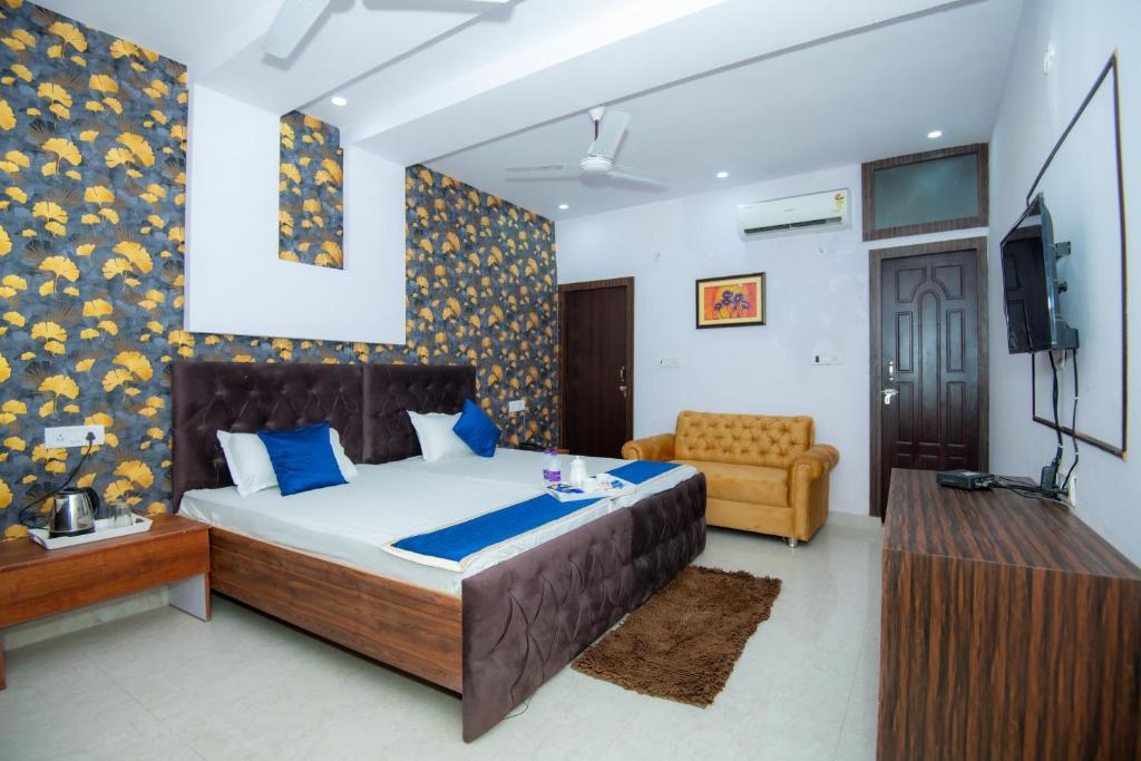 een slaapkamer met een bed, een bank en een televisie bij Hotel Blossom in Lucknow