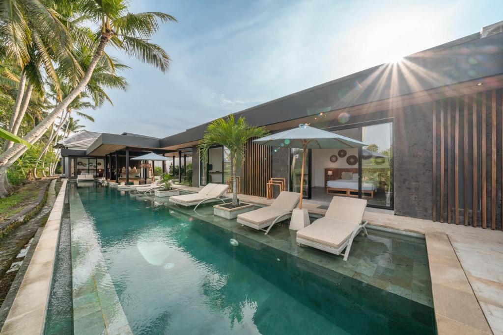 a swimming pool with lounge chairs and a house at Villa Surga - 4BR Heavenly Ricefields View Villa in Ubud in Ubud