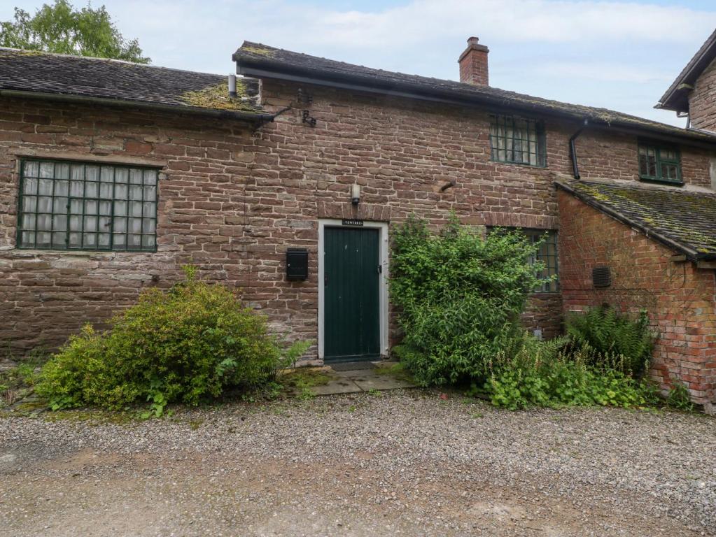 an old brick house with a green door at Yew Tree Cottage in Leominster