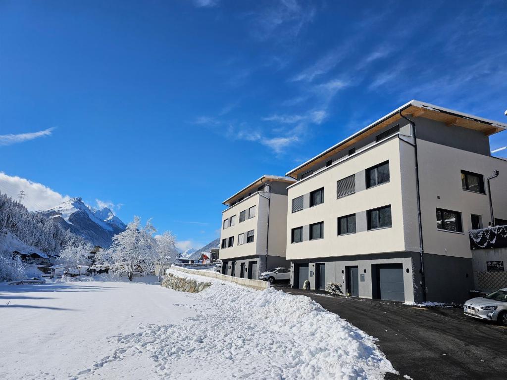 a building with snow on the ground next to a street at Apartment Eflin in Fulpmes