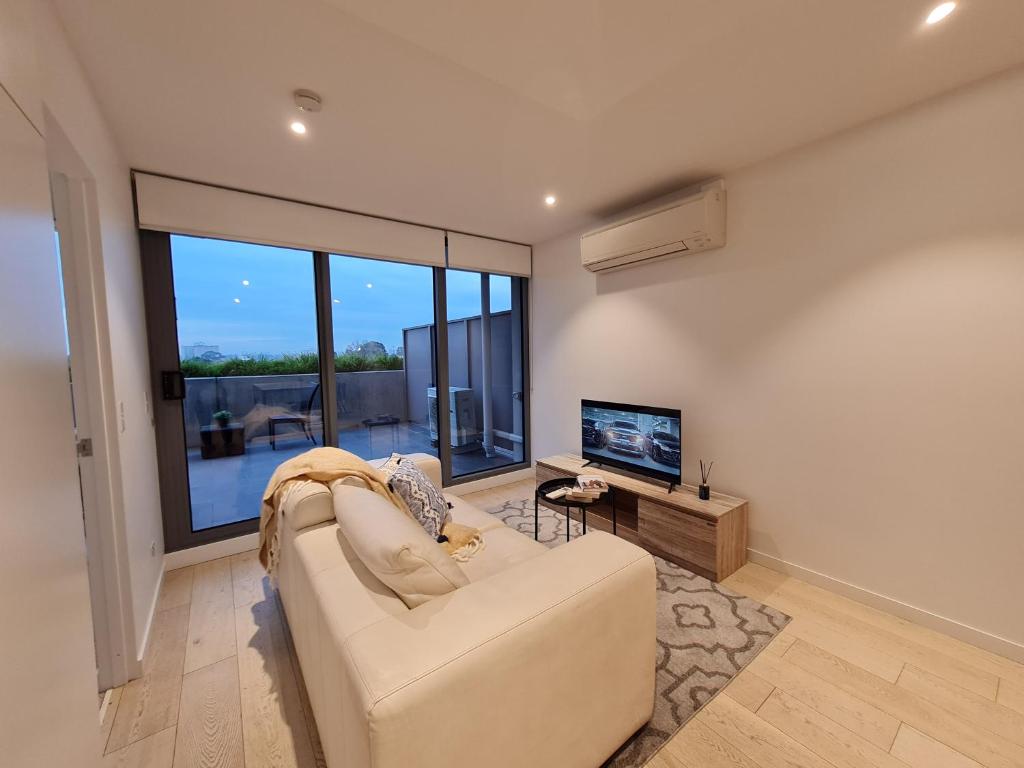 uma sala de estar com um sofá e uma televisão de ecrã plano em Serenity 1br Flemington Balcony Pool Free Park em Melbourne