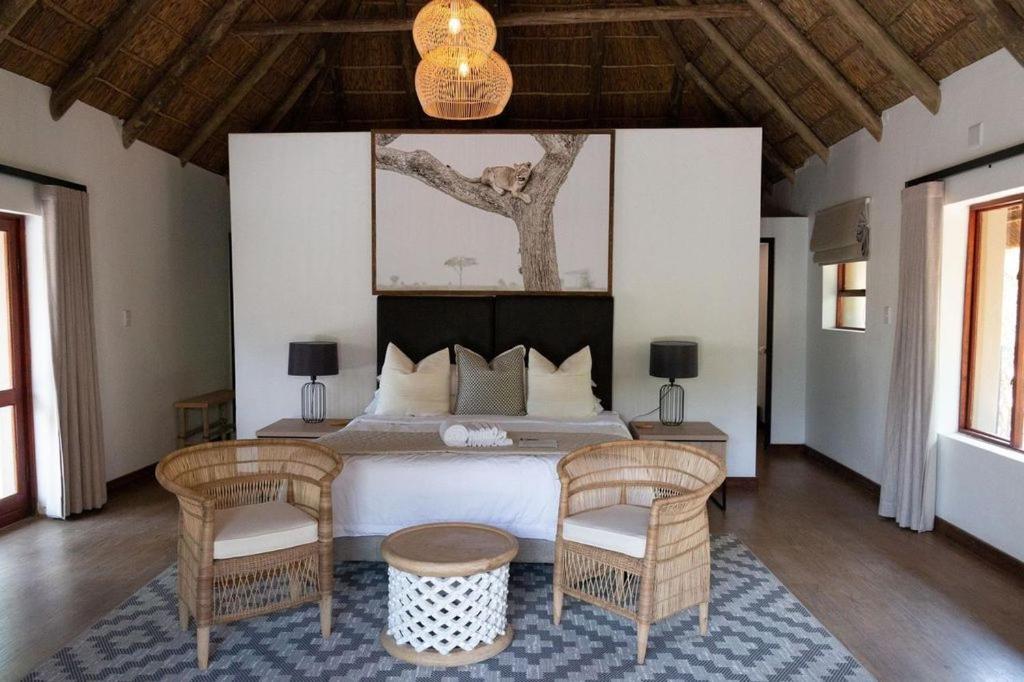a bedroom with a large bed and two chairs at Mologa River Lodge in Rust de Winter