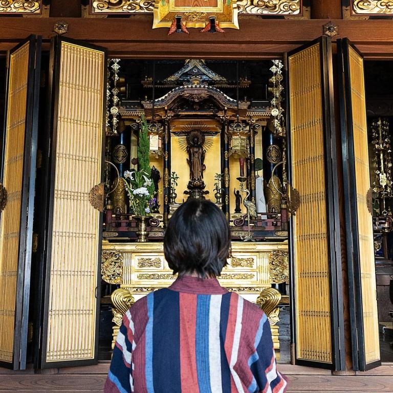 una mujer sentada frente a un santuario en 湖北 寺の宿- GuestHouse去-来-現Ko-Rai-Gen en Nagahama