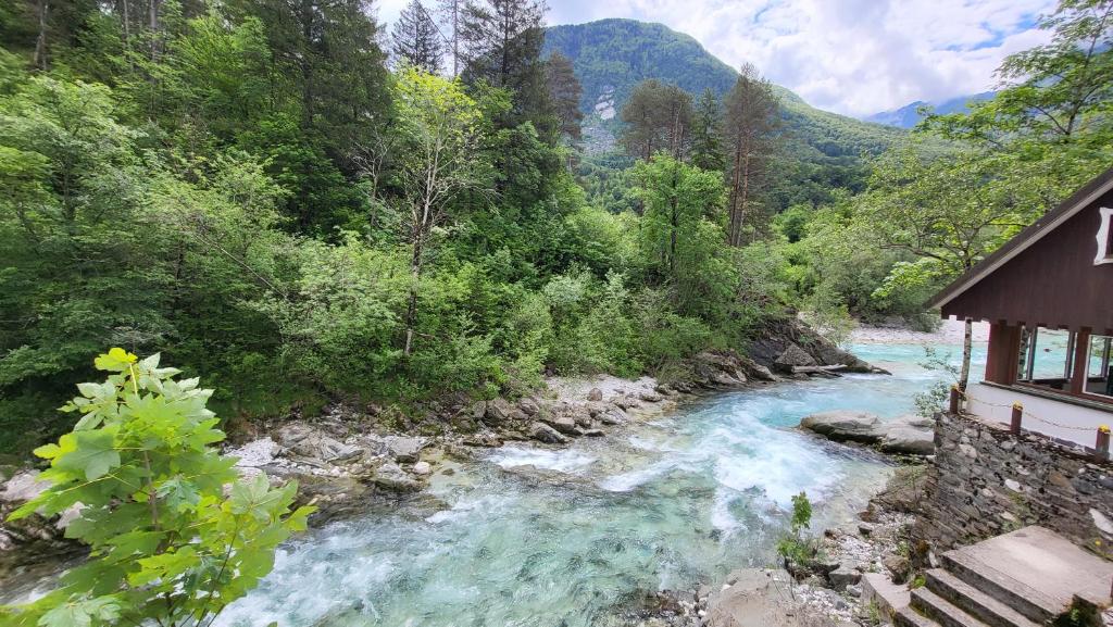 a river next to a building next to a mountain at Apartment Luka at Soča & Koritnica confluence in Bovec