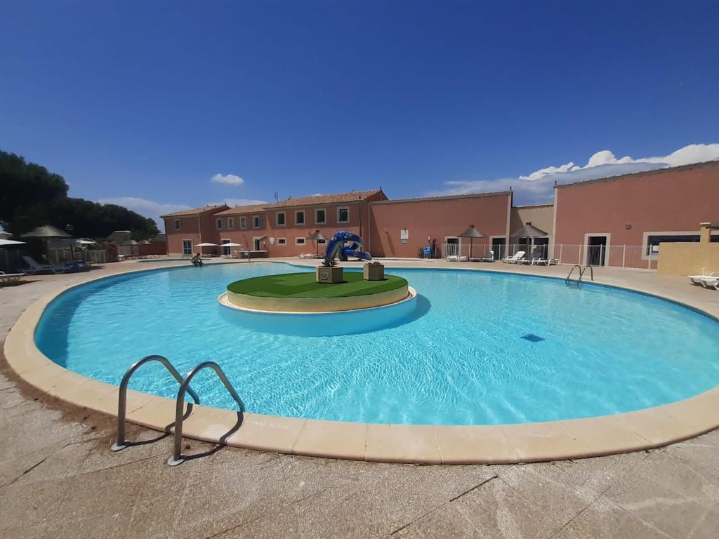 une grande piscine devant un immeuble dans l'établissement Mas sympathique entre étang et mer !, au Barcarès