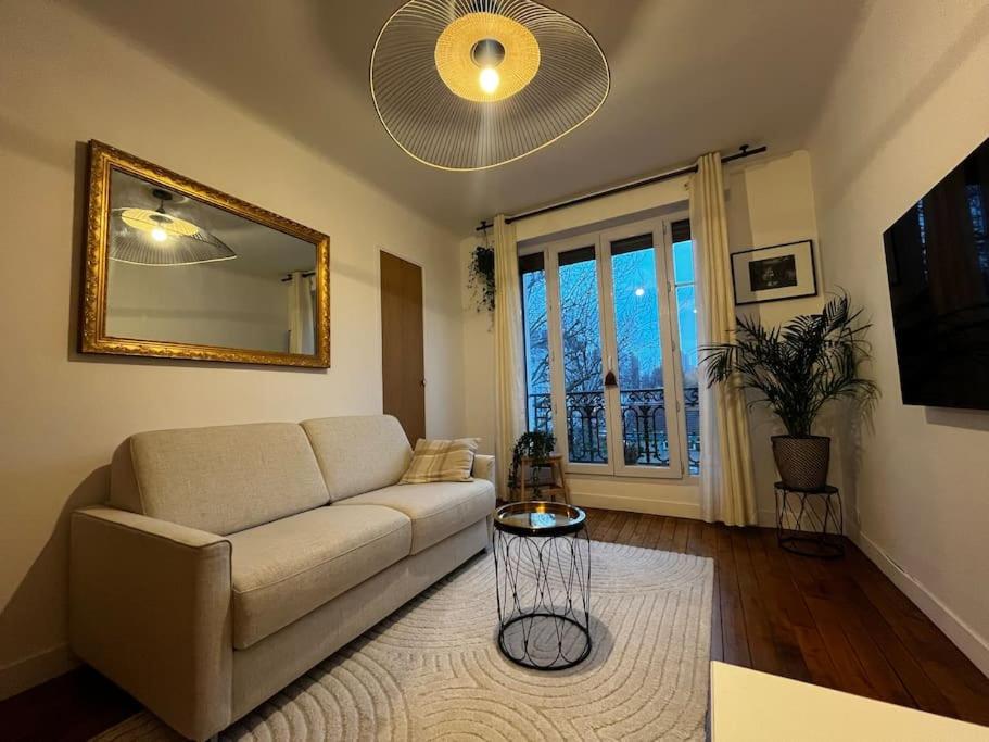 un salon avec un canapé et un miroir dans l'établissement Cosy - Magnifique vue sur parc Georges Brassens, à Paris