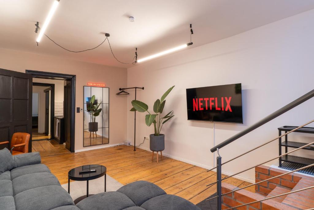 a living room with a couch and a tv on a wall at bevoflats - Stilvolles Souterrain am Mehringdamm in Berlin