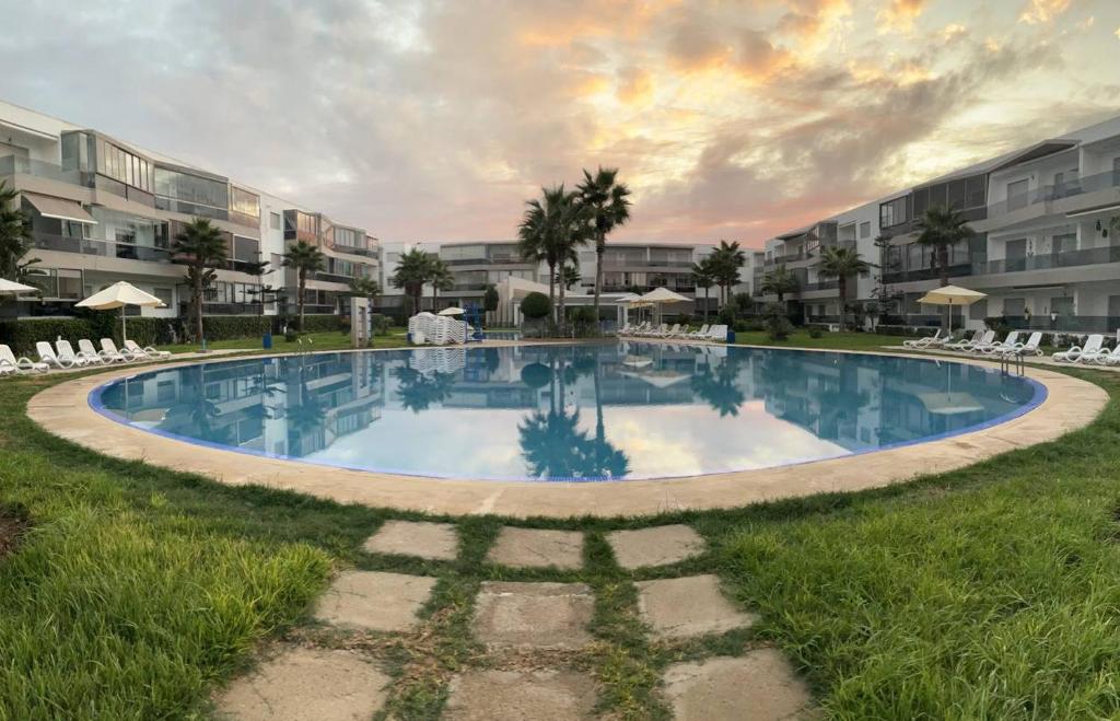 a large swimming pool in a yard with chairs at Nice Apartment in Blanca Beach in Sidi Rahal