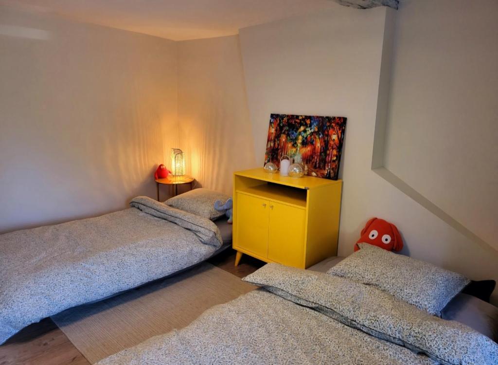 sypialnia z 2 łóżkami i żółtą szafką w obiekcie L'Arsouille Gîte Rural Doische w mieście Doische