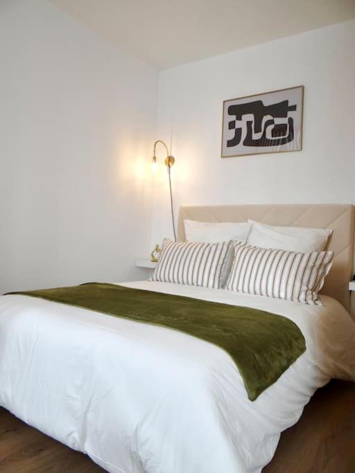 - un grand lit blanc avec une couverture et des oreillers verts dans l'établissement Le Blum Studio *Hyper-Centre* avec *CANAL PLUS*, à Amiens
