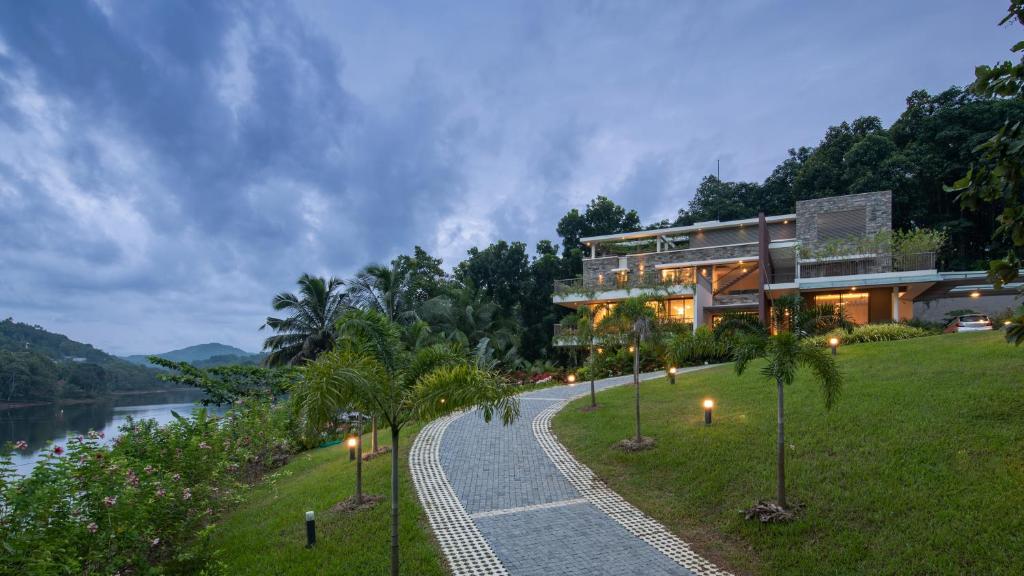 a building with a pathway next to a river at Premium 5 BR full pool villa by lake close to Vagamon in Muttam
