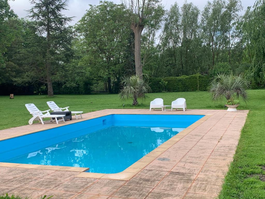 una piscina en un patio con 2 sillas de césped en Grand appartement indépendant de trois chambres proche Disney, en Isles-lès-Villenoy