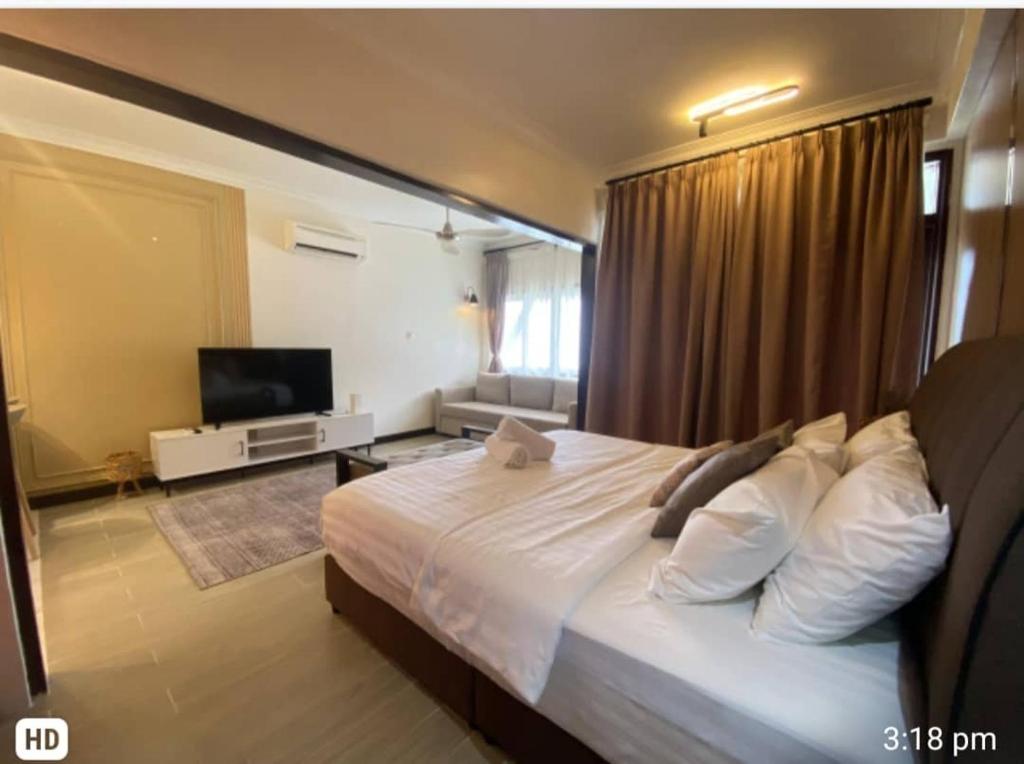 1 dormitorio con 1 cama grande y TV en The Green Lagoon en Pantai Cenang