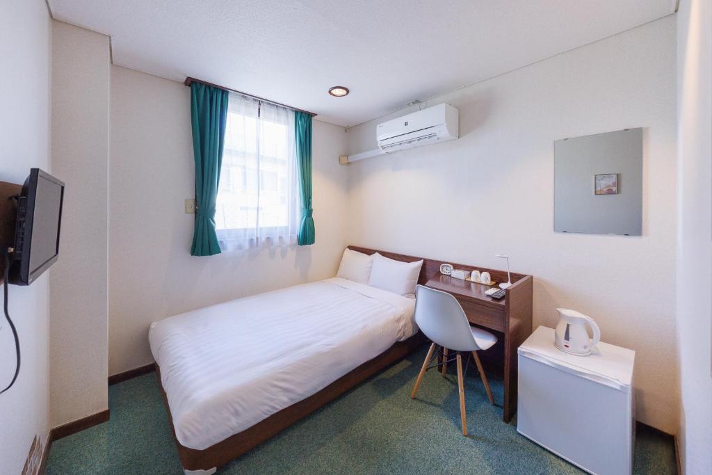 1 dormitorio con cama, escritorio y ventana en ホテルノマド日立 en Hitachi