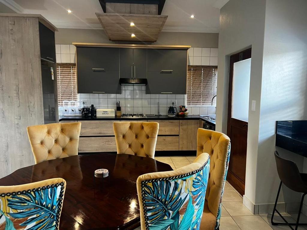 a kitchen with a wooden table and chairs and a counter at Sasavona Luxury Cottage - 631 Euphoria Golf & Lifestyle Estate in Naboomspruit