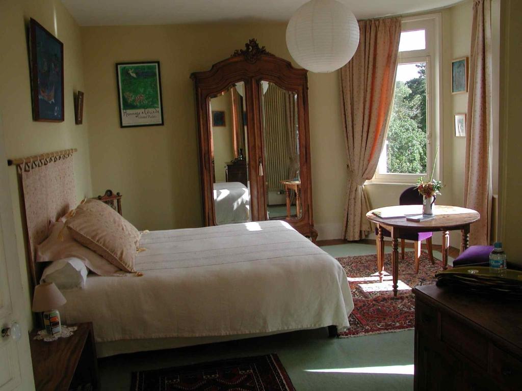 a bedroom with a bed and a mirror and a table at Chambres d'Hôtes les Charmettes in Étretat