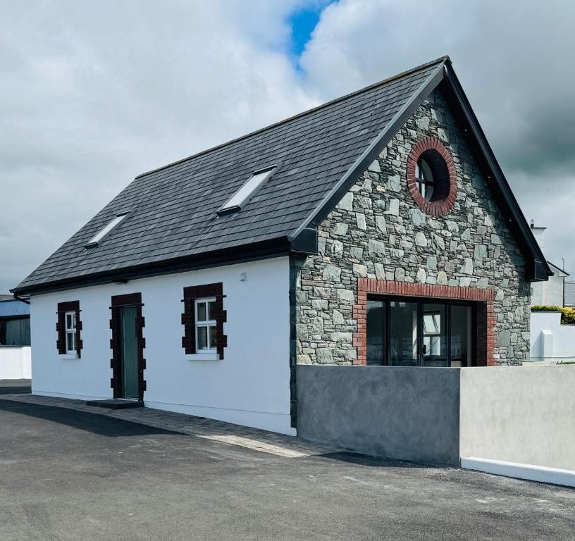 a small white building with a black roof at De Búrca Cottage KERRY in Brackhill