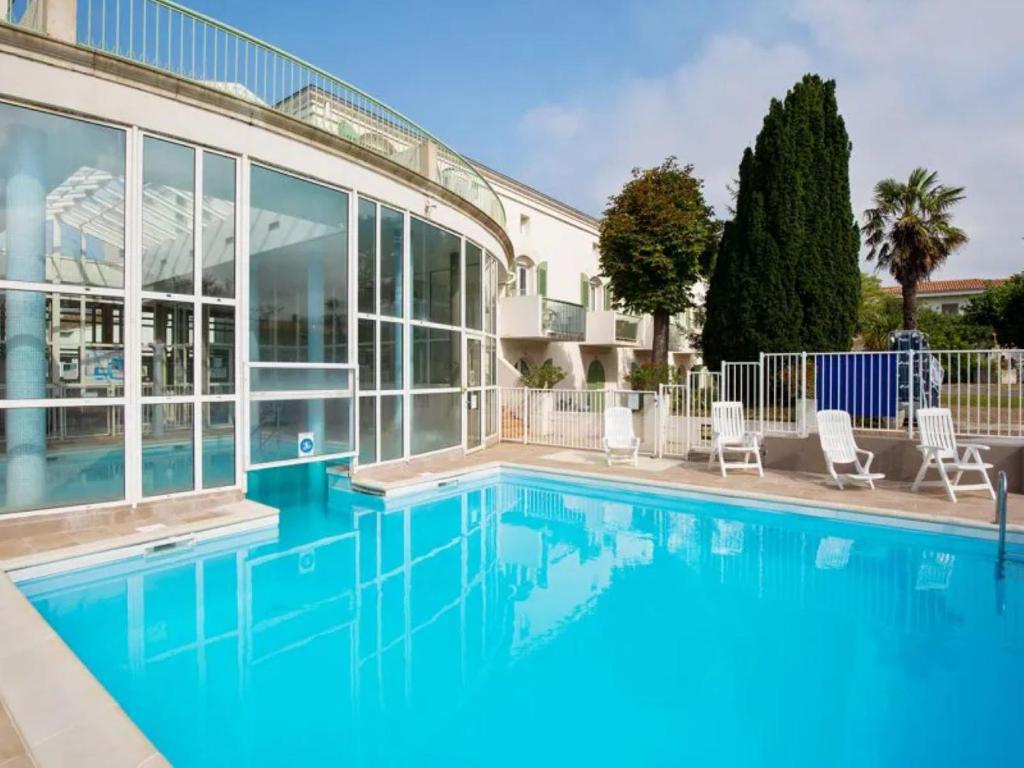 - une piscine d'eau bleue en face d'un bâtiment dans l'établissement NATICE Bel appartement dans résidence privée, à Saint-Martin-de-Ré