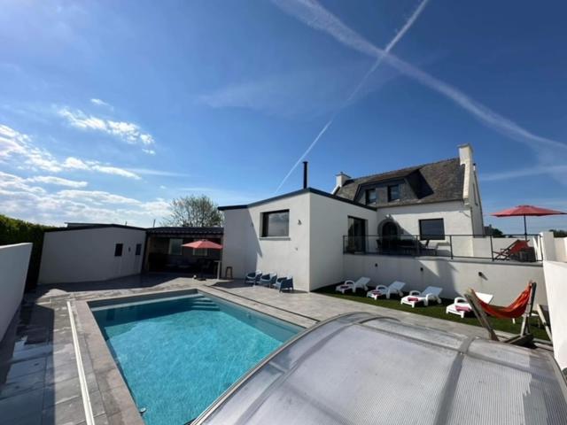 une piscine devant une maison dans l'établissement Entre Terre et Mer 12 Personnes Espace Piscine chauffée, à Landivisiau