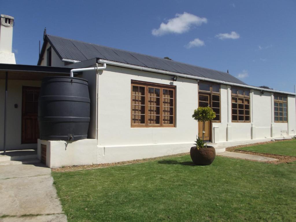 a white building with a black roof at Karsrivier Cottage in Bredasdorp