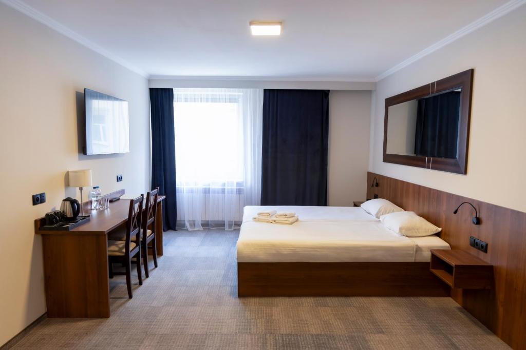 ワルシャワにあるヒット ホテルのベッド、テーブル、デスクが備わる客室です。