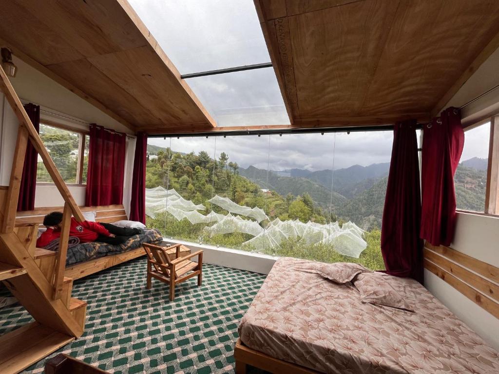 ein Schlafzimmer mit einem großen Fenster in einem Zug in der Unterkunft Stargazing Glass Lodge Himachal Pradesh Thachi in Mandi