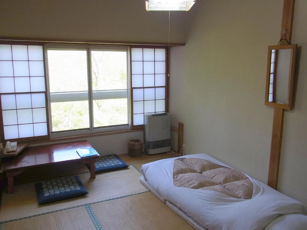 een slaapkamer met een bed, een bureau en ramen bij Fuji-Hakone Guest House in Hakone