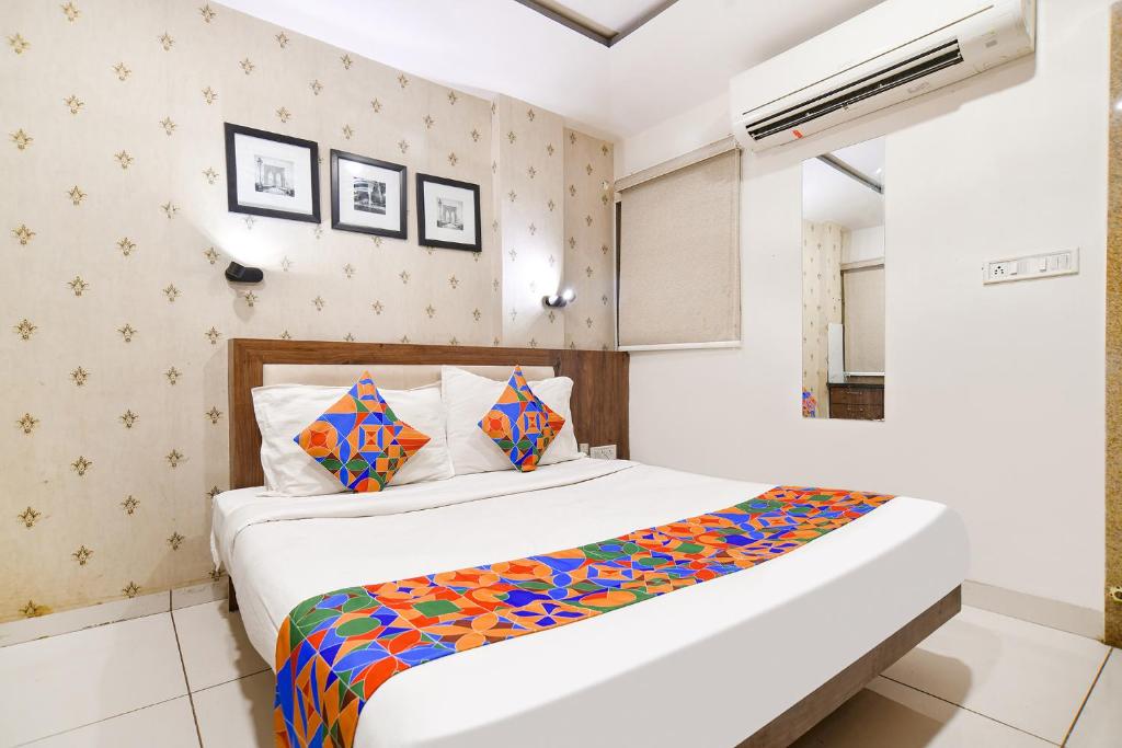 印多爾的住宿－FabHotel Shree Ram Palace，一间卧室配有一张带彩色床单的大床