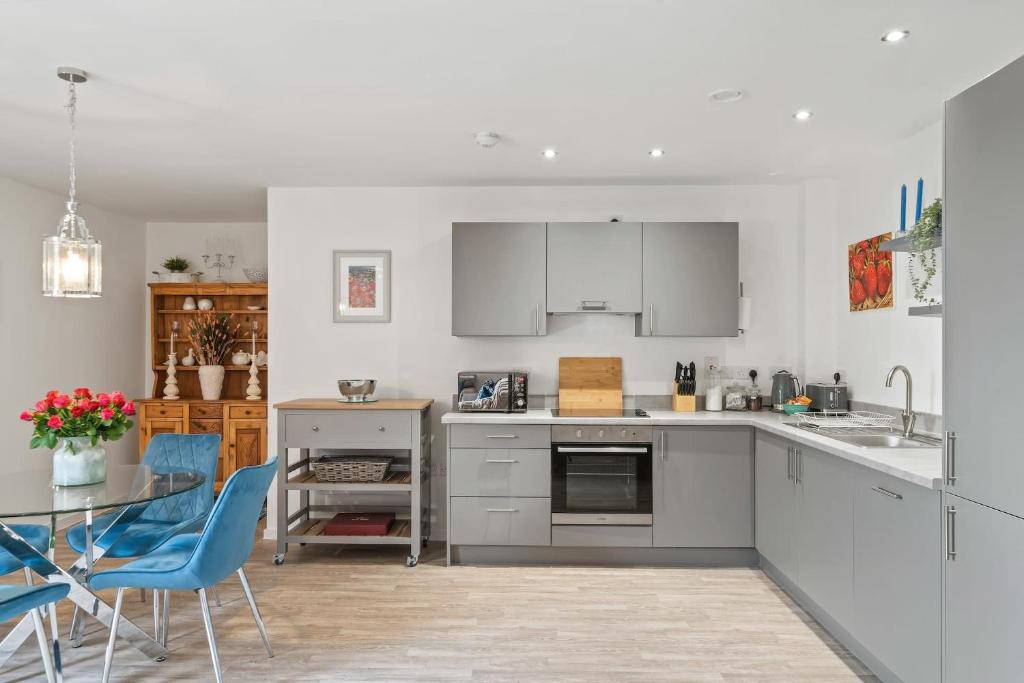 eine Küche mit weißen Schränken sowie einem Tisch und Stühlen in der Unterkunft Modern Apartment Private Parking Central Taunton in Taunton