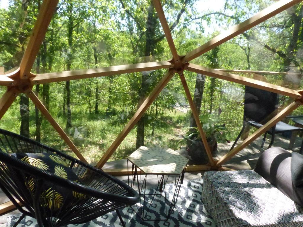 un porche cubierto con vistas al bosque en Dôme géodésique au cœur de la forêt, en Montignac