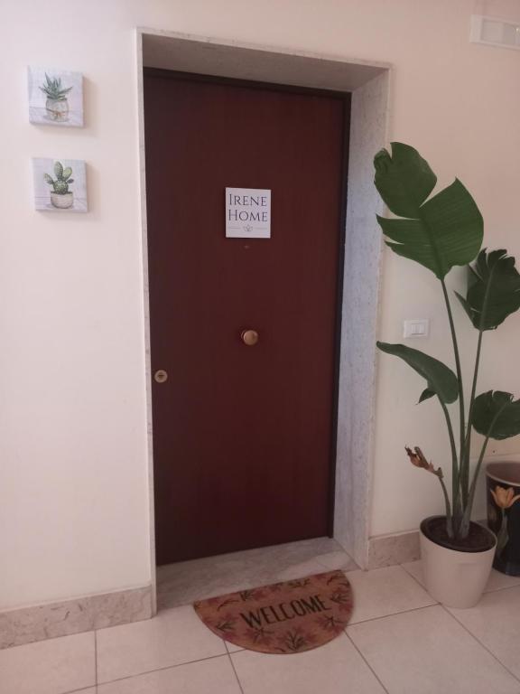 uma porta castanha com um sinal ao lado de uma planta em Irene Home em Siracusa