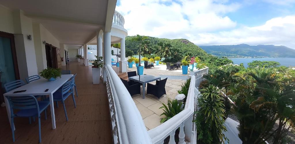 Petit Amour Villa, Seychelles في فيكتوريا: شرفة مع طاولات وكراسي وإطلالة على المحيط