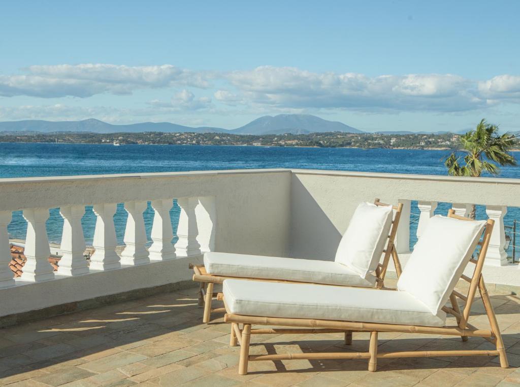 Duas cadeiras sentadas numa varanda com vista para o oceano em Teresa Spetses em Spetses