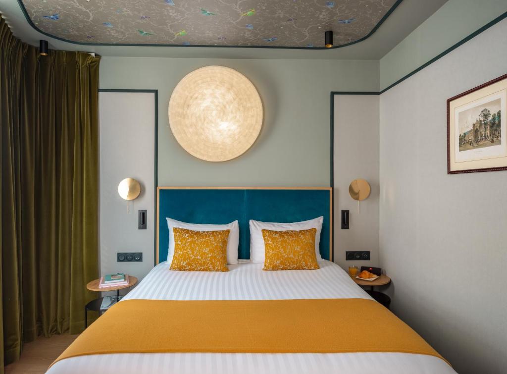 パリにあるホテル ルイゾンのベッドルーム1室(大型ベッド1台、青いヘッドボード付)